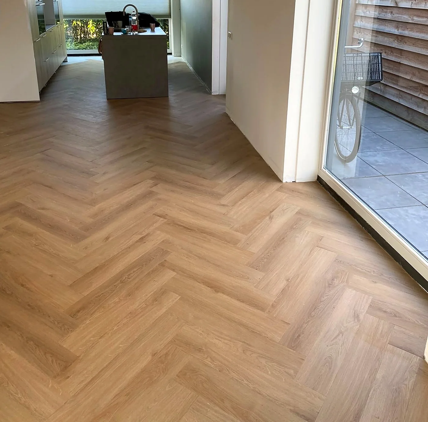 Afgewerkte visgraatvloer in een woonkamer met open keuken